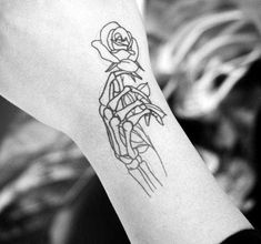 a woman's arm with a tattoo on it that has a skeleton holding a rose