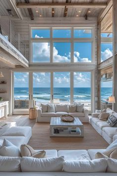 a living room with white couches and large windows overlooking the ocean on a sunny day