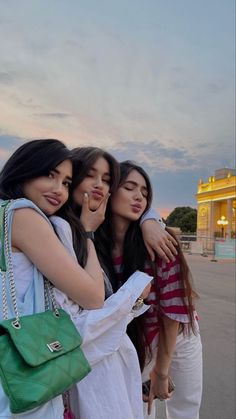 three girls are hugging each other in front of a building