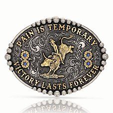 The Montana Silversmith� Pain Is Temporary Attitude Belt Buckle is solid cast white metal alloy with a silver- and gold-toned finish. Antiqued with light engraving, the dark background contrasts nicely with the 2-toned design. A gold-toned bull and rider sit center, surrounded by the words "Pain is temporary" "Victory lasts forever" and 2 flowers on either side with center stones. Framed with silver-toned beading. Oval buckle with standard 1.5" belt swivel. Montana Armor� protective finish to pr Elegant Silver Jewelry With Engraved Logo, Silver Brass Jewelry With Engraving Option, Classic Gold Jewelry With Engraved Logo, Gold Jewelry With Engraved Logo For Formal Occasions, Silver Metal Jewelry With Engraving Option, Western Silver Metal Jewelry, Western Style Silver Metal Jewelry, Gold Stamped Metal Jewelry, Western Style Engraved Gold Jewelry