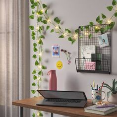 a laptop computer sitting on top of a wooden desk next to a potted plant