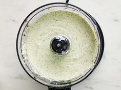 a food processor filled with green sauce on top of a white counter