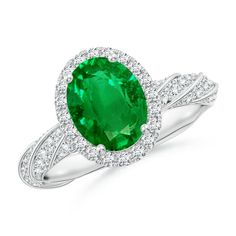 an oval shaped emerald and diamond ring in white gold with diamonds around the shans