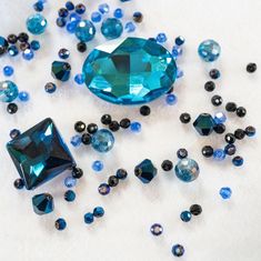 some blue and black jewels are laying on the ground together, with one large diamond surrounded by smaller ones