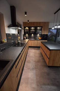 an empty kitchen with black counter tops and wooden cabinets, along with dark wood flooring