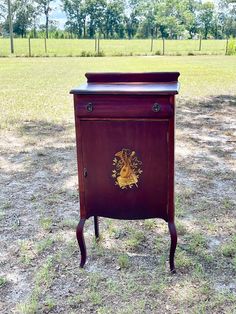 an old fashioned wooden cabinet in the middle of a field with grass and trees behind it