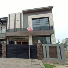 a house with a for sale sign on the front door and black gated entrance