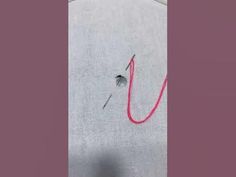 a piece of cloth with red thread on it and a hole in the fabric that has been stitched into