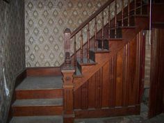 an old wooden stair case next to a wall papered with damask and patterns