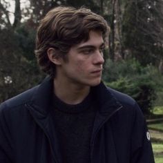 a young man standing in the woods looking off into the distance