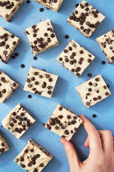 chocolate chip brownies with white frosting on a blue surface, being cut into squares