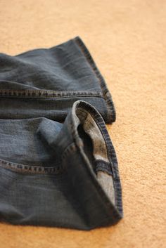 a pair of jeans laying on the floor with one pocket open and another partially closed