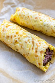 two burritos sitting on top of a piece of wax paper