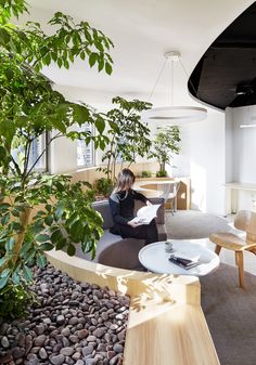 two pictures of a woman sitting on a couch in an office with plants and desks