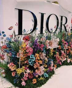 a display with flowers and plants in front of a dior sign that says dior