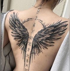 the back of a woman's tattoo with black wings and arrows on her chest