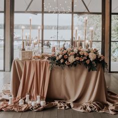 the table is set up with candles and flowers for an elegant wedding reception in front of large windows