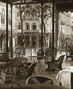 an old photo of tables and chairs on a patio with flags flying in the wind