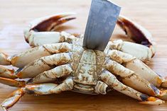 a large crab with a knife stuck in it's claws on a wooden surface