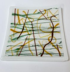 a white plate with yellow and green swirls on it's surface, against a white background