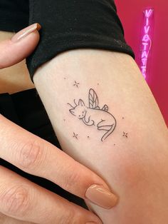 a woman's arm with a small tattoo of a cat and stars on it