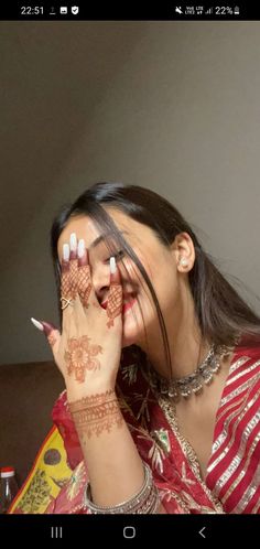 a woman holding her hands to her face with hendi tattoos on it's arms