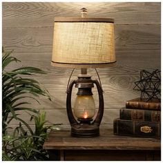 a lamp that is on top of a table next to some books and a potted plant