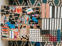 an assortment of crafting supplies are displayed on a wooden crate with black and white patterned wallpaper