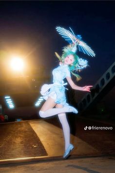 a woman is dancing on the street at night with her arms outstretched and legs spread out