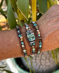 This 3-wrap bracelet that can also be worn as a hat band is hand made with natural turquoise, abalone, and picture jasper with an abalone focal in the center  The stones and focal are bound on natural light brown distressed leather.  It measures approximately 19.5" to 29" with a silver button and 8 loop button holes for closure.  It has a flexible fit so it can either be worn around the average wrist 3 times as a bracelet or worn once around a hat as a hat band.   This wrap will be packaged in a Adjustable Earthy Hand Wrapped Bracelet, Earthy Adjustable Hand Wrapped Bracelet, Bohemian Adjustable Wrap Bracelet For Healing, Rustic Adjustable Hand Wrapped Bracelet, Adjustable Natural Stone Wrap Bracelet For Festivals, Unique Natural Stones Wrap Bracelet For Healing, Unique Hand Wrapped Healing Wrap Bracelet, Unique Adjustable Wrap Bracelet For Beach, Adjustable Natural Stones Wrap Bracelet