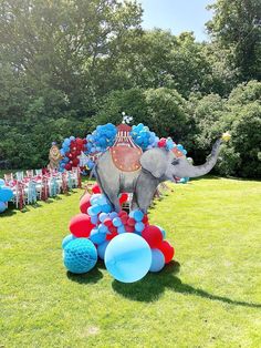 an elephant is standing on top of balloons in the middle of a lawn with tables and chairs