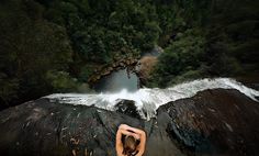 a woman standing on top of a rock next to a river in the middle of a forest