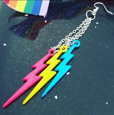 three different colored plastic toothbrushes hanging from a silver chain on a black surface