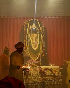 a man standing in front of a statue with candles on the ground next to it