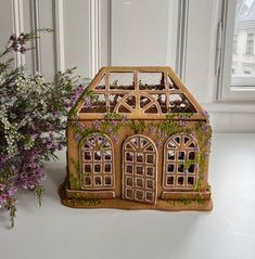 a house shaped planter sitting next to a vase filled with flowers