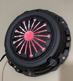 a black and pink fan sitting on top of a white wall