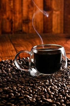 a cup of coffee sitting on top of a pile of coffee beans