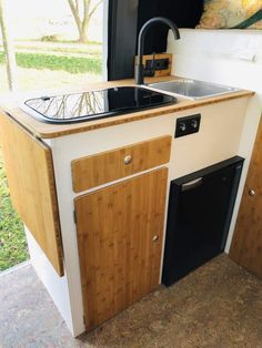 the kitchen sink is made out of wood and has a black faucet in it