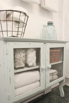 a white cabinet with glass doors and towels