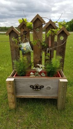 a wooden planter with plants growing out of it in the middle of a field