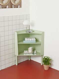 a corner shelf in the corner of a room next to a potted plant