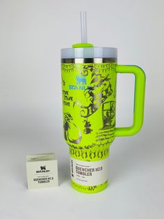 a green travel mug next to a matchbox on a white surface with the lid up