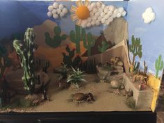 a desert scene made out of cardboard with fake cactus and cacti in the background