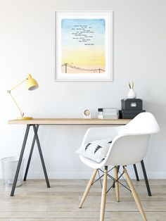 a white chair sitting in front of a wooden desk with a black and white painting on it