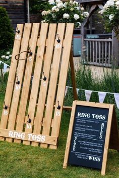 a wooden sign sitting on top of a lush green field next to a chalkboard