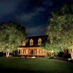 a house lit up at night with trees in the front yard