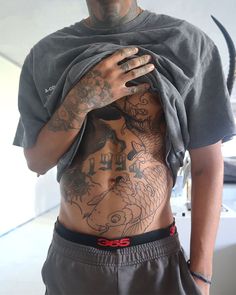 a man with tattoos on his chest and shirt over his body is holding onto a gray t - shirt