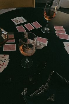 a table topped with cards next to a glass of wine and a chain on top of it