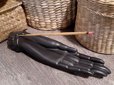 a black hand holding a wooden stick on top of a table next to wicker baskets