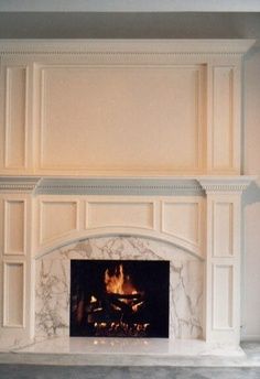 a fireplace with a fire place in the middle and white paint on the wall behind it